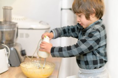 Sevimli küçük çocuk, yemek hazırlayan çocuk olarak ailesine yardım ediyor.