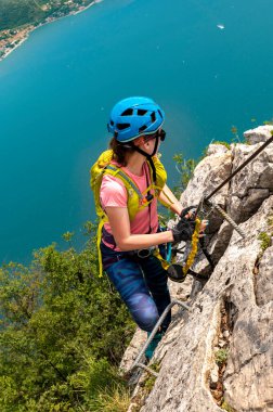 Beautiful woman on via ferrata trail, above Garda lake clipart