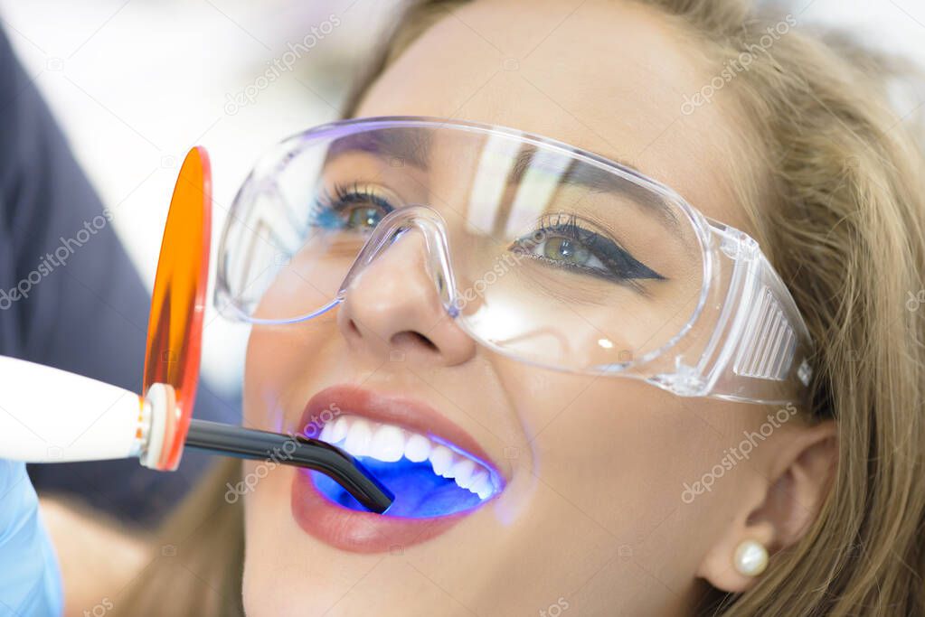 Dentist using ultraviolet lamp on a female patient