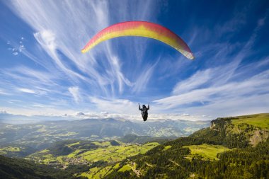 Paraglider flying over mountains clipart