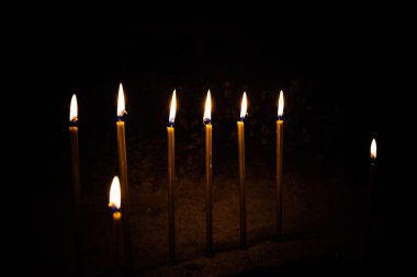 Sarı mumlar kilisede siyah arka planda yanar.