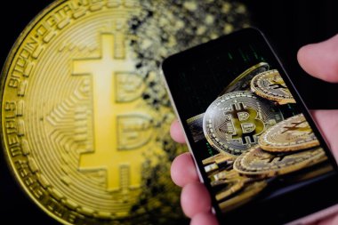 Cep telefonu tutan adam, bitcoin simgesi, borsa arkaplanı grafikli blok zinciri, kripto para birimleri veya bitcoin konsepti