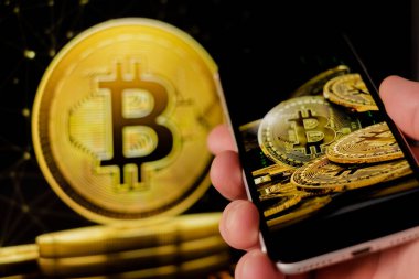 Cep telefonu tutan adam, bitcoin simgesi, borsa arkaplanı grafikli blok zinciri, kripto para birimleri veya bitcoin konsepti