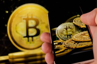 Cep telefonu tutan adam, bitcoin simgesi, borsa arkaplanı grafikli blok zinciri, kripto para birimleri veya bitcoin konsepti