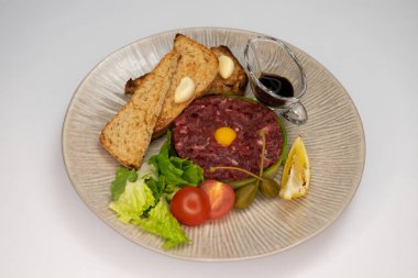 Beyaz arka planda et ve sebzeli şık bir yemek.