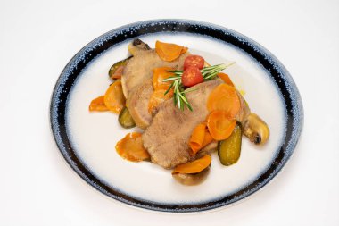 Beyaz arka planda et ve sebzeli şık bir yemek.