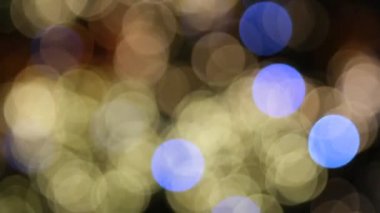 Bokeh ışıkları kapanıyor. Mutlu Noel tatili dekorasyonu. Mutlu yıllar. Parlak mavi ve beyaz yumuşak odaklı ışıklar yanıp sönüyor. Odaklanma özellikleri. Lens Bokeh. İşaret fişeği. Karanlık Arkaplan. Kapat..