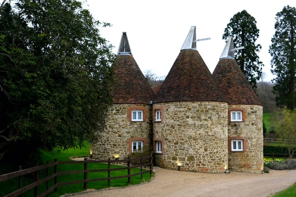 Typical converted Oast House in a remote setting in a village in Kent, England, UK. Oast houses in group constructed with white cowls on top in South of England.