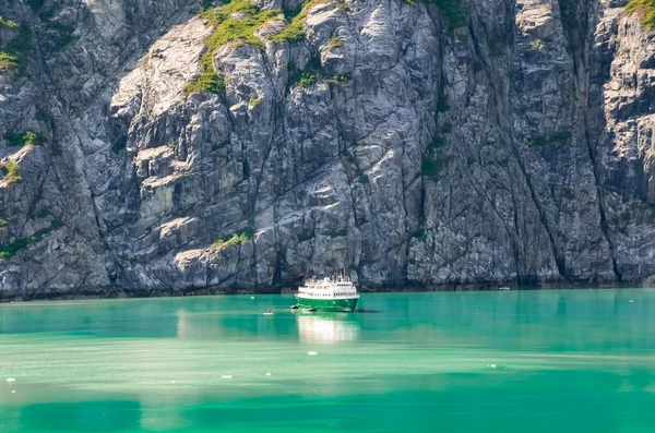 Alaska landscape mountains and water with the boat. Mountains reflection in the water. Remote location, unplugged. Wild beauty in nature. Untouched environment. Turquoise water color.