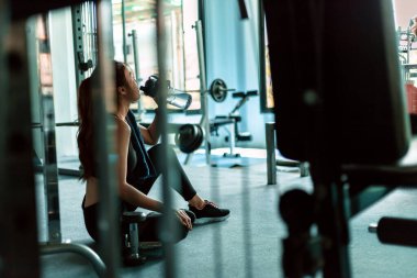 Kadın spor salonunda antremandan sonra mola verip su içiyor..