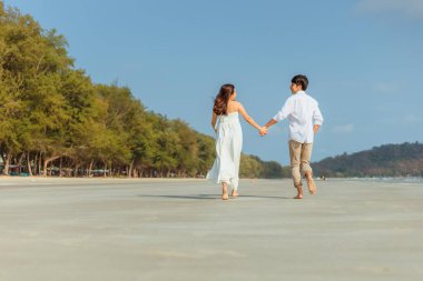 El ele tutuşup plajda koşan genç çifte bayılıyorum. Tatil ve meslek kavramı.