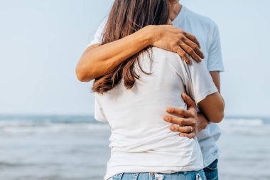 Romantik çift yazın sahilde birbirlerine sarılırlar. Balayı, seyahat, tatil, yaz konsepti. 