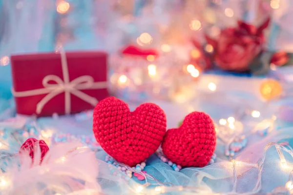 kalp şeklinde, köpük boncuklar, tüy, hediye kutusu ve mavi kumaş üzerinde hafif dekoratif bokeh. Aşk, Sevgililer Günü ve tatil konsepti.