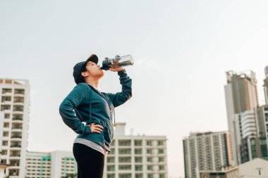 Susamış kadın sporcu ara veriyor. Koştuktan sonra su içiyor..