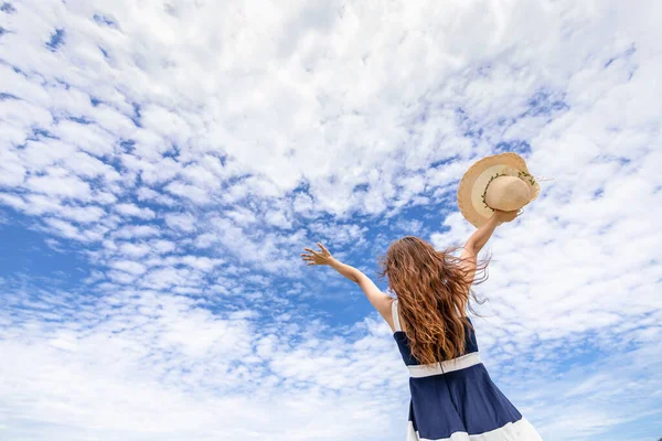 Young woman raise a hat in the sky on the beach. Summer vocation island.