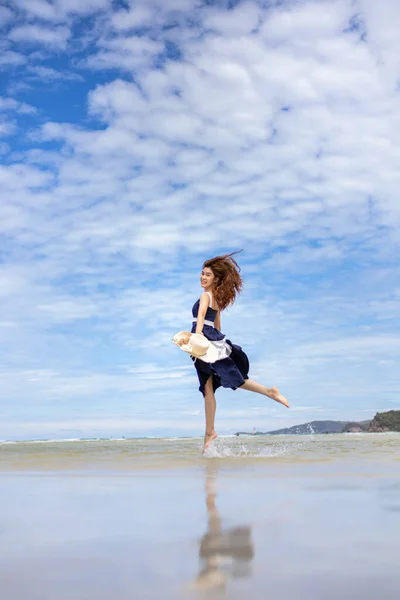 Woman barefoot jump in the water on summer along wave of sea water and sand on the beach.