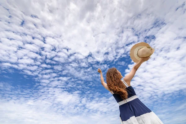 Young woman raise a hat in the sky on the beach. Summer vocation island.