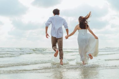 El ele tutuşup plajda koşan genç çifte bayılıyorum. Tatil ve meslek kavramı.