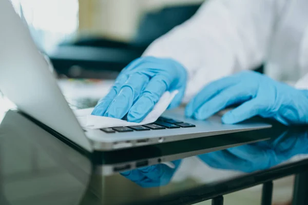 Scientists are cleaning labtop by alcohol and tissue after checking and testing virus on labtop at home.