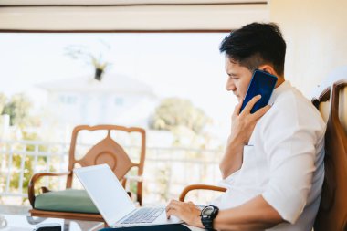 İş yerindeki işadamı telefonda konuşuyor ve elinde bir fincan kahve tutuyor ve iş yerindeki bilgisayar ekranına bakıyor..