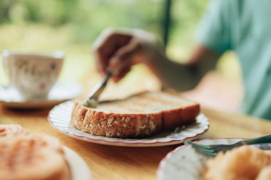 Bıçak sabah kahvaltısında kızarmış ekmeğe tereyağı sürüyor. Kahve ve tatlı konsepti.