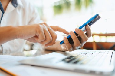 İş yerinde çalışan ve akıllı telefon ve defter bilgisayarı kullanan genç işadamı