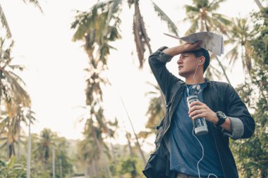 Sırt çantalı bir adam terini silip ormanda su şişesini tutuyor. Sırt çantası seyahat kavramı.