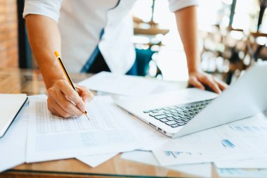 Yönetici işadamı rapor hazırlıyor, dengeyi hesaplıyor. Masadaki gelir tabloları, grafikleri ve verileri analiz etme işi.