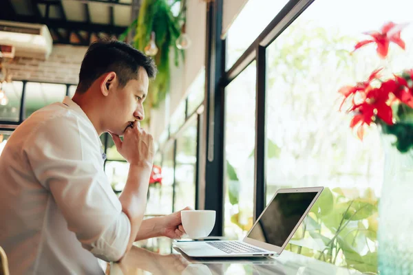 businessman holding coffee cup in hands and computer on table in coffee shop. Young freelancer drink coffee and working.