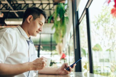 İş yerinde çalışan ve akıllı telefon ve defter bilgisayarı kullanan genç işadamı
