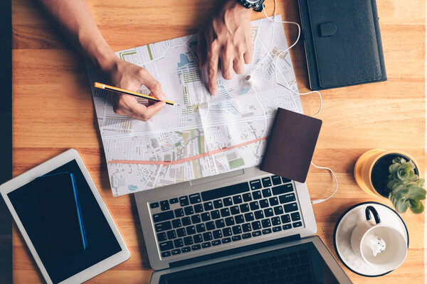 Tourist planning vacation use pen pointing on the map and other travel accessories around on the table. Vocation, travel, holidays and backpack concept.