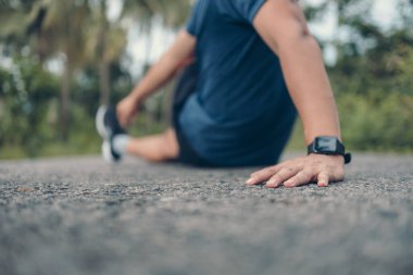 Genç adam koşmadan önce parkta geriniyor. Genç adam parktaki fitness antrenmanından önce antrenman yapıyor. Sağlıklı ve egzersiz yapan genç adam ormanda ısınıyor..