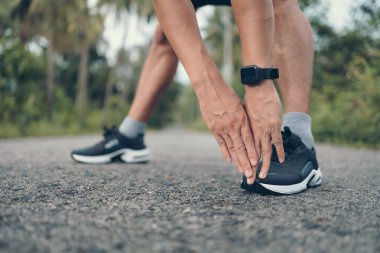 Genç adam koşmadan önce parkta geriniyor. Genç adam parktaki fitness antrenmanından önce antrenman yapıyor. Sağlıklı ve egzersiz yapan genç adam ormanda ısınıyor..