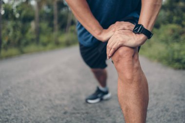 Genç adam koşmadan önce parkta geriniyor. Genç adam parktaki fitness antrenmanından önce antrenman yapıyor. Sağlıklı ve egzersiz yapan genç adam ormanda ısınıyor..