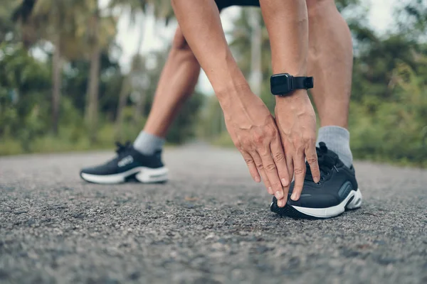 Genç adam koşmadan önce parkta geriniyor. Genç adam parktaki fitness antrenmanından önce antrenman yapıyor. Sağlıklı ve egzersiz yapan genç adam ormanda ısınıyor..