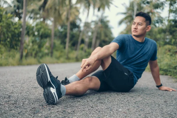 Genç adam koşmadan önce parkta geriniyor. Genç adam parktaki fitness antrenmanından önce antrenman yapıyor. Sağlıklı ve egzersiz yapan genç adam ormanda ısınıyor..