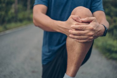 Genç adam koşmadan önce parkta geriniyor. Genç adam parktaki fitness antrenmanından önce antrenman yapıyor. Sağlıklı ve egzersiz yapan genç adam ormanda ısınıyor..