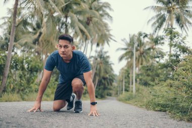 Koşmaya başlayan sporcu ormanda yolda poz verir. Başlangıç ve hedef kavramı.