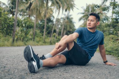 Genç adam koşmadan önce parkta geriniyor. Genç adam parktaki fitness antrenmanından önce antrenman yapıyor. Sağlıklı ve egzersiz yapan genç adam ormanda ısınıyor..