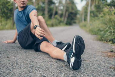 Genç adam koşmadan önce parkta geriniyor. Genç adam parktaki fitness antrenmanından önce antrenman yapıyor. Sağlıklı ve egzersiz yapan genç adam ormanda ısınıyor..