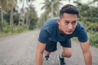 Koşmaya başlayan sporcu ormanda yolda poz verir. Başlangıç ve hedef kavramı.