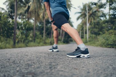 Genç adam koşmadan önce parkta geriniyor. Genç adam parktaki fitness antrenmanından önce antrenman yapıyor. Sağlıklı ve egzersiz yapan genç adam ormanda ısınıyor..