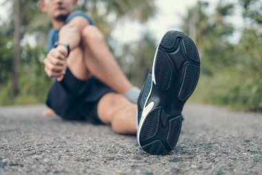 Genç adam koşmadan önce parkta geriniyor. Genç adam parktaki fitness antrenmanından önce antrenman yapıyor. Sağlıklı ve egzersiz yapan genç adam ormanda ısınıyor..