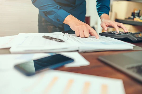 Accounting woking with data sheet on the office desk. Calculator with accounting report and financial statement on desk.