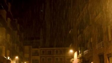 4k 'lık sağanak yağmur ve yıldırımla dolu bir şehirde gece vakti. Şehir ışıklarıyla renklendirilmiş turuncu.