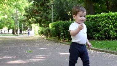 Bir çocuğun şehir parkında bir güvercini işaret ederek yürümeye ve kovalamaya başladığı video 4k.