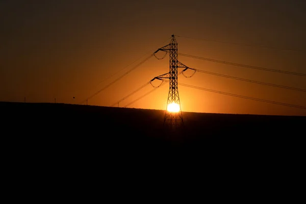 Солнце Прячется Середине Электрической Башни Несколькими Горами Заднем Плане Против — стоковое фото