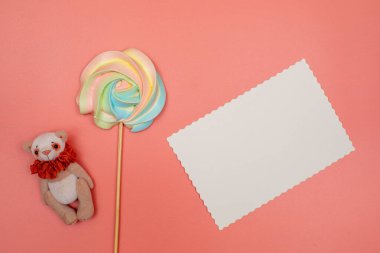 Boş beyaz kartpostal, çubukta gökkuşağı kreması ve pembe arka planda oyuncak ayı. Noel, Yeni Yıl, Sevgililer Günü, Uluslararası Kadınlar Günü veya Anneler Günü kompozisyonu.