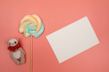 Boş beyaz kartpostal, çubukta gökkuşağı kreması ve pembe arka planda oyuncak ayı. Noel, Yeni Yıl, Sevgililer Günü, Uluslararası Kadınlar Günü veya Anneler Günü kompozisyonu.