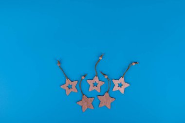 Yeni yıl ve Noel oyuncakları mavi arka planda. Lazer, tahta yıldız heykelciklerini kesti. Metin için boş alanı olan bir kartpostal kompozisyonu. Yeni yıl ve Noel konsepti. Kopyalama alanı olan düz. 